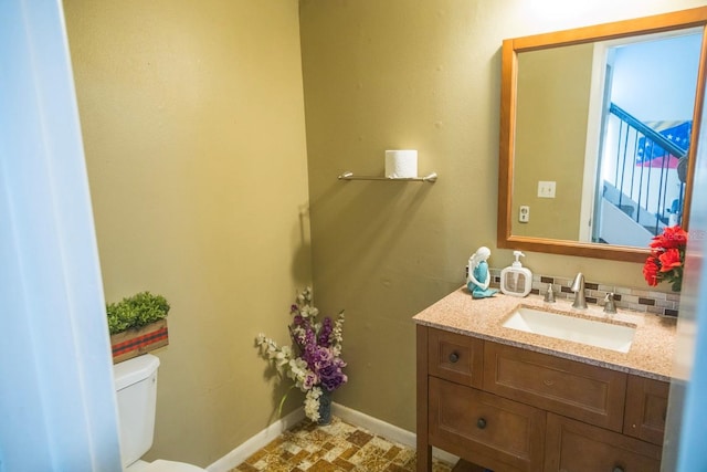 bathroom featuring tasteful backsplash, toilet, vanity, and baseboards