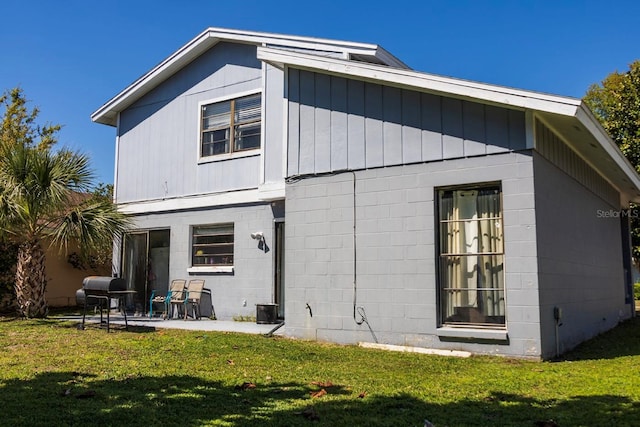 back of property featuring a patio, concrete block siding, and a yard