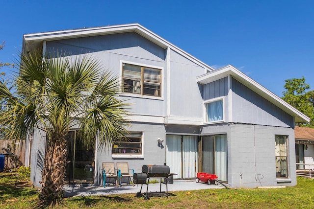 back of house featuring concrete block siding and a patio area