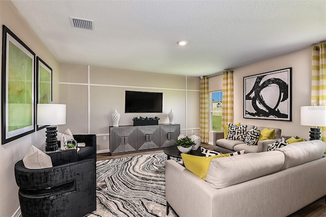 living room with visible vents, a textured ceiling, and wood finished floors