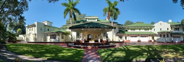 rear view of property featuring a yard, metal roof, and stucco siding