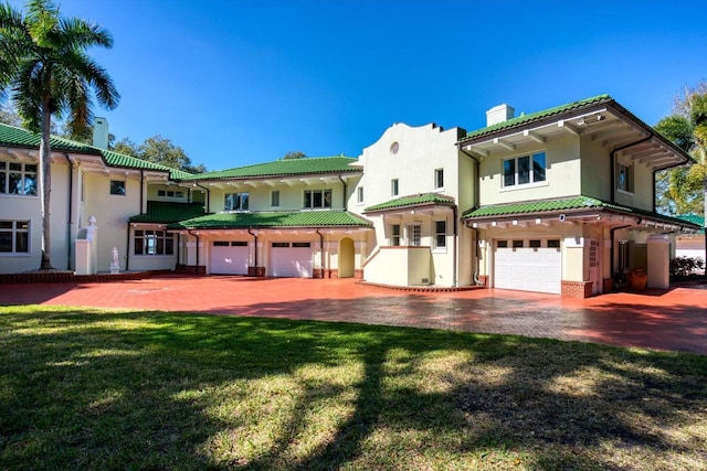 view of front of house featuring stucco siding, driveway, a front yard, a garage, and a chimney