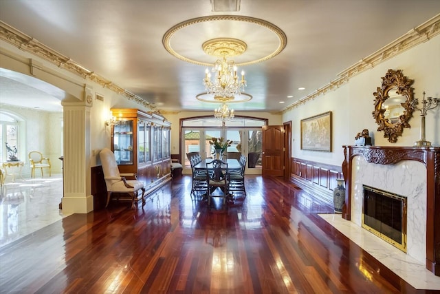 dining area featuring crown molding, a chandelier, a wainscoted wall, hardwood / wood-style flooring, and arched walkways