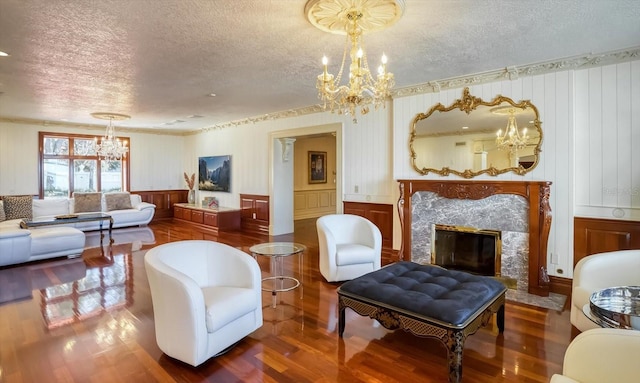 living room featuring a premium fireplace, a textured ceiling, an inviting chandelier, and wood finished floors