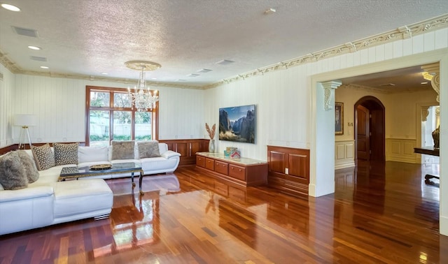 living area with a chandelier, ornamental molding, wood finished floors, arched walkways, and a textured ceiling