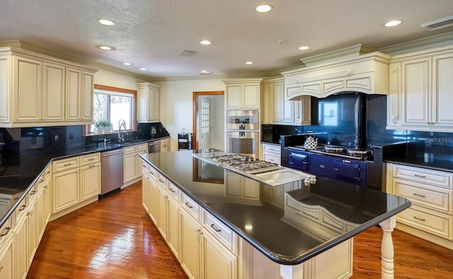 kitchen featuring dark countertops, cream cabinetry, appliances with stainless steel finishes, and a center island