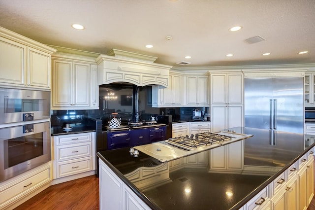kitchen with dark countertops, recessed lighting, stainless steel built in fridge, and wood finished floors