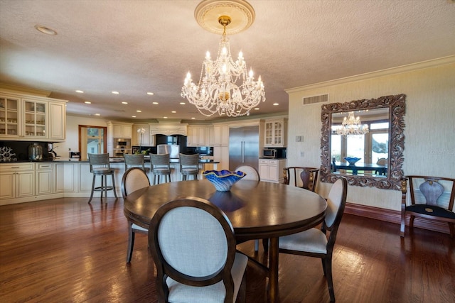 dining room featuring visible vents, a notable chandelier, ornamental molding, a textured ceiling, and dark wood finished floors