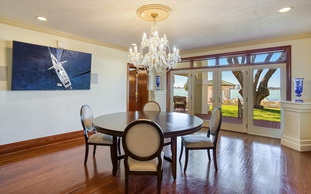 dining room with ornamental molding, a textured ceiling, wood finished floors, french doors, and an inviting chandelier