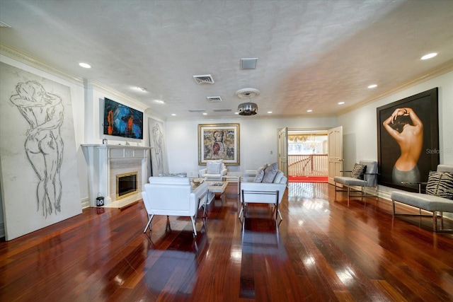 living area with visible vents, a fireplace, crown molding, and hardwood / wood-style flooring