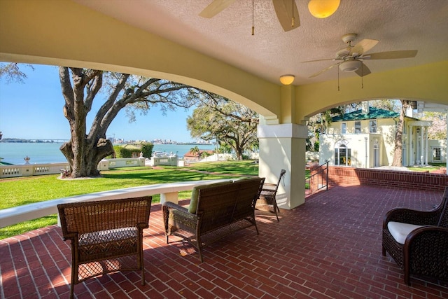 view of patio / terrace with a ceiling fan and a water view