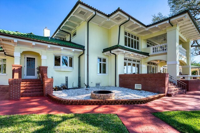rear view of house with an outdoor fire pit, stucco siding, and a chimney