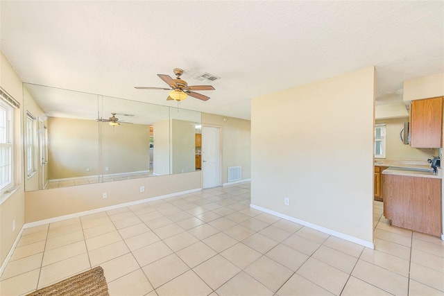 unfurnished room with light tile patterned floors, visible vents, baseboards, and a ceiling fan