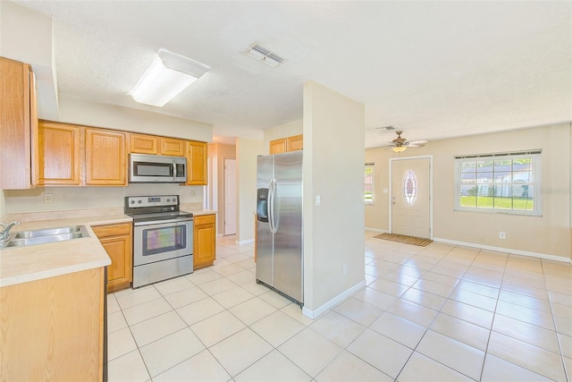 kitchen with light tile patterned floors, visible vents, a sink, stainless steel appliances, and light countertops