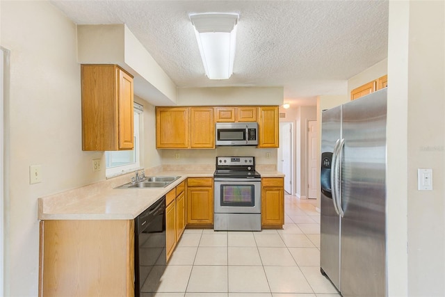 kitchen with a sink, a textured ceiling, stainless steel appliances, light countertops, and light tile patterned floors