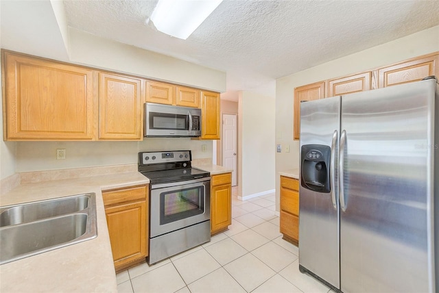 kitchen featuring light tile patterned floors, appliances with stainless steel finishes, light countertops, and a sink