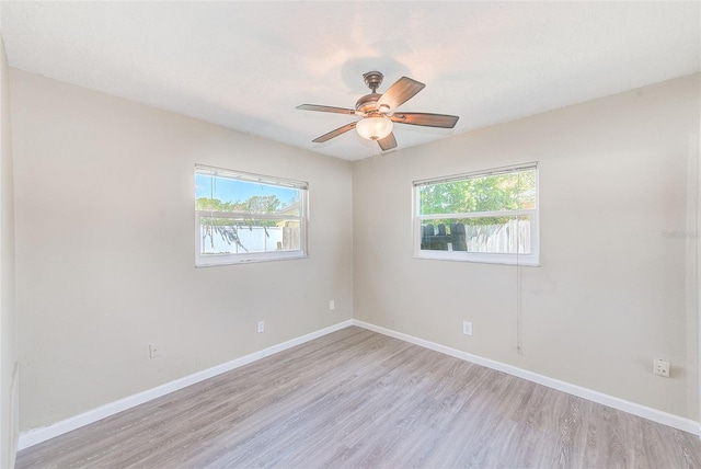 spare room featuring baseboards, plenty of natural light, and light wood finished floors