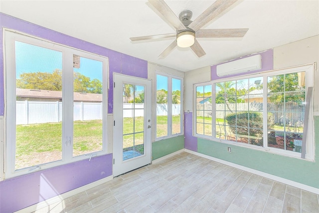 unfurnished sunroom with a wall unit AC and a ceiling fan