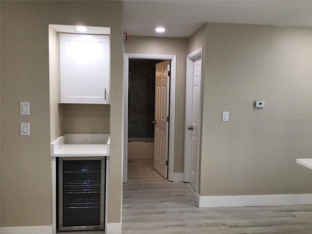 hallway featuring recessed lighting, baseboards, light wood-style floors, and beverage cooler