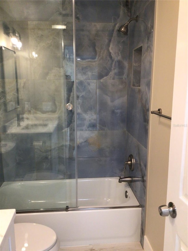 bathroom featuring toilet, vanity, and shower / bath combination with glass door