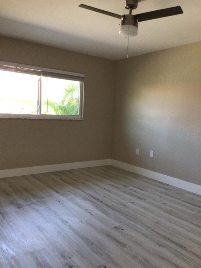 empty room with baseboards, wood finished floors, and a ceiling fan