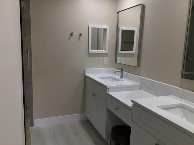 full bath featuring two vanities, baseboards, and a sink