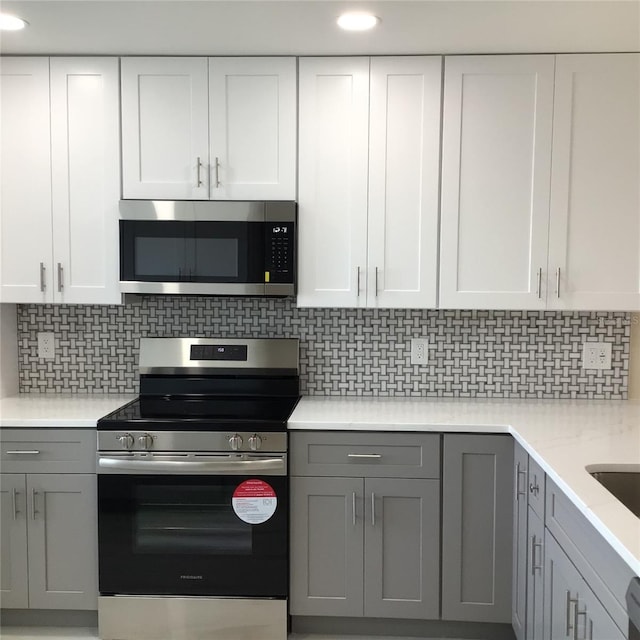 kitchen featuring backsplash, gray cabinets, and appliances with stainless steel finishes