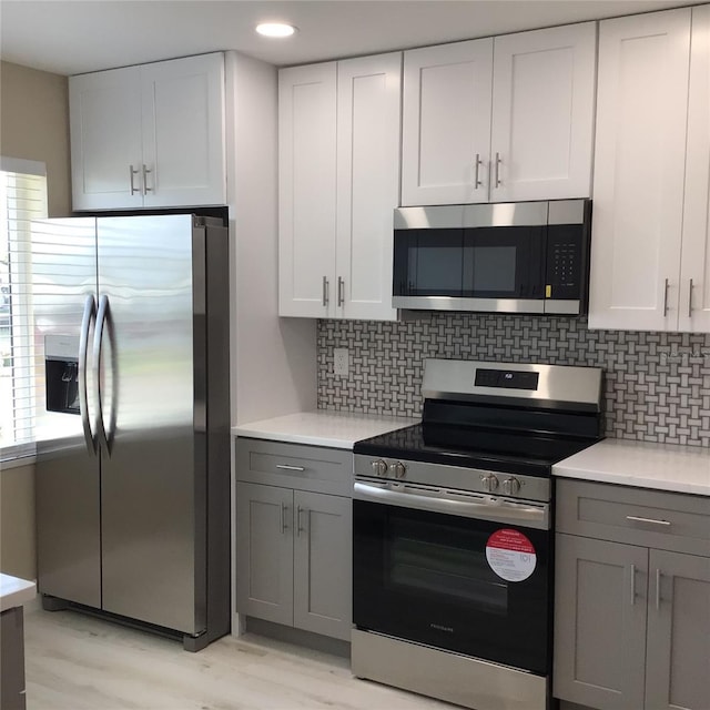 kitchen with decorative backsplash, light countertops, appliances with stainless steel finishes, and gray cabinetry