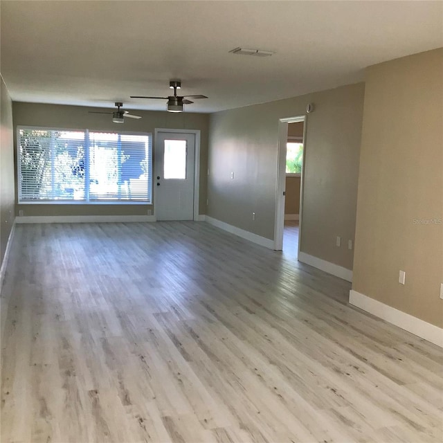 empty room with visible vents, plenty of natural light, baseboards, and wood finished floors