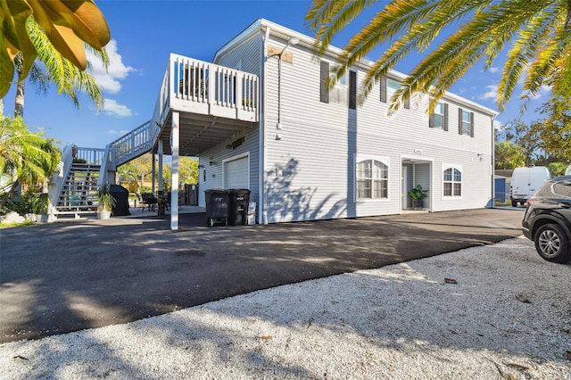 view of property exterior featuring driveway, an attached garage, and stairs