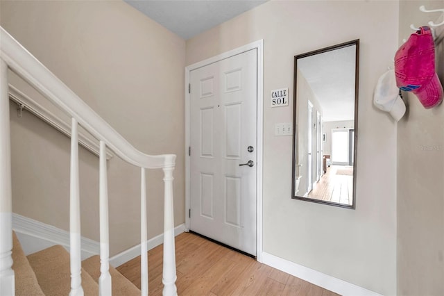 entrance foyer with baseboards, wood finished floors, and stairs