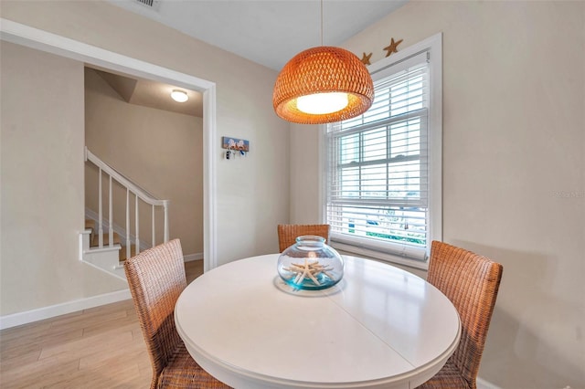 dining space featuring stairway, light wood-style flooring, and baseboards