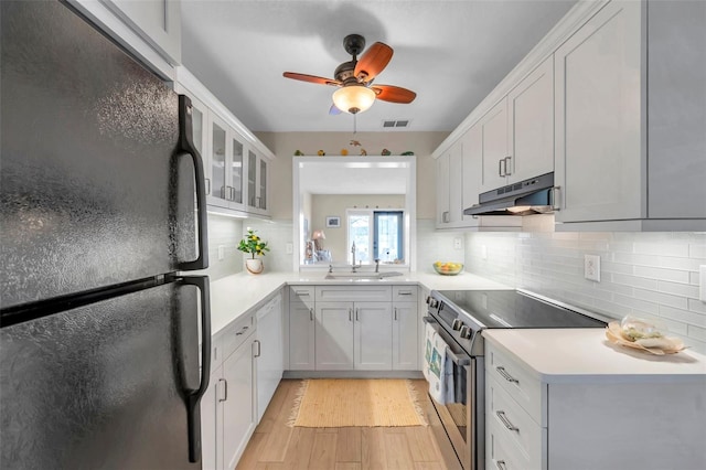 kitchen with under cabinet range hood, a sink, freestanding refrigerator, stainless steel electric range oven, and dishwasher