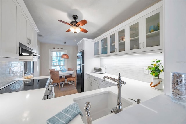 kitchen featuring decorative backsplash, stainless steel range with electric stovetop, light countertops, and freestanding refrigerator