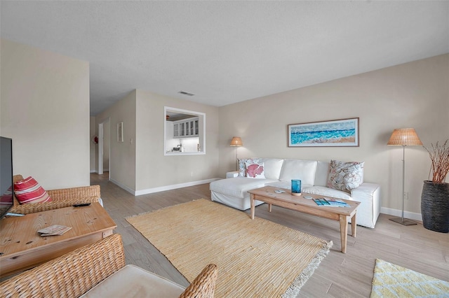 living area featuring light wood finished floors, visible vents, and baseboards