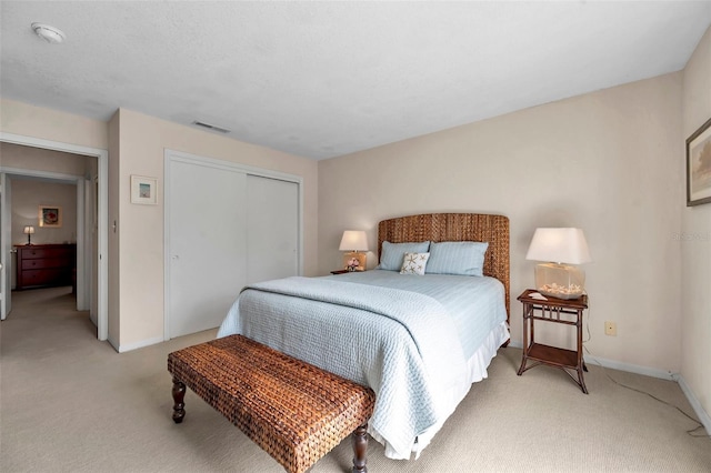 bedroom featuring baseboards, visible vents, a closet, and light carpet