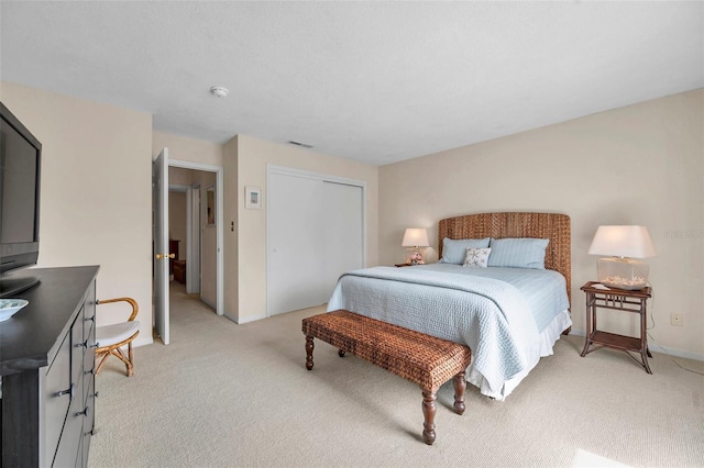 bedroom featuring a closet, visible vents, light colored carpet, and baseboards