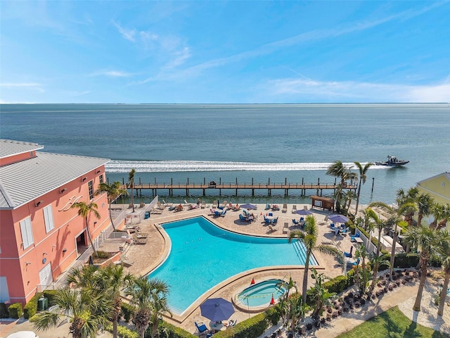 community pool featuring a patio area, a water view, and a hot tub