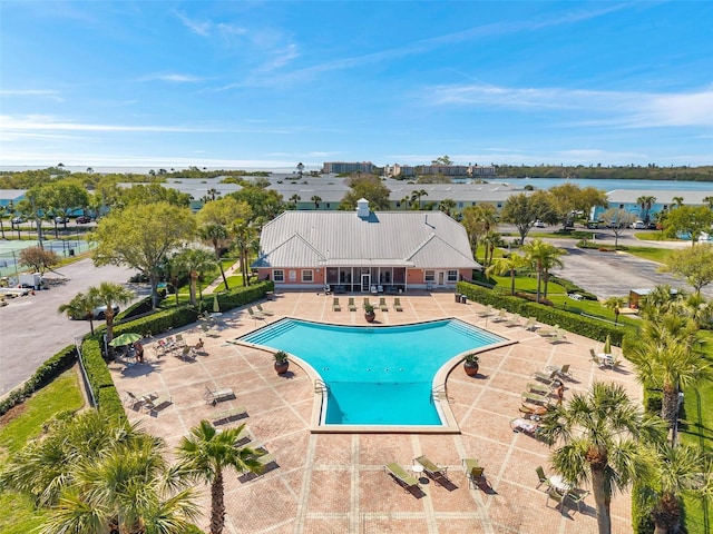 pool with a patio, fence, and a water view