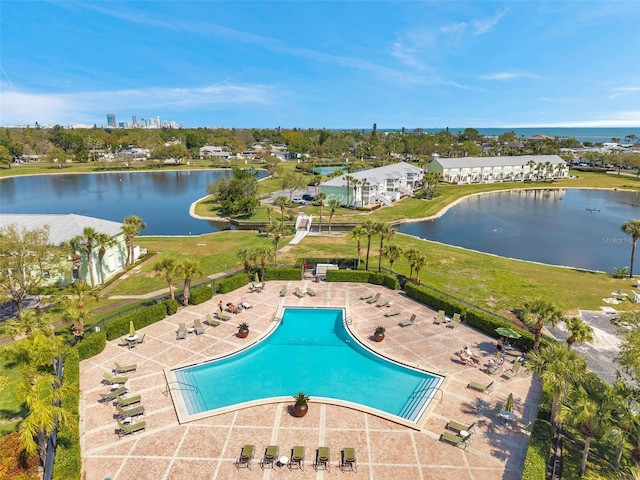 community pool with a patio, fence, and a water view