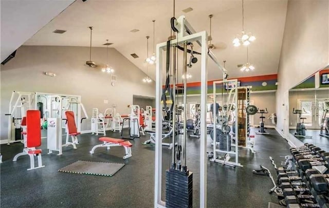 exercise room featuring a chandelier, visible vents, high vaulted ceiling, and baseboards