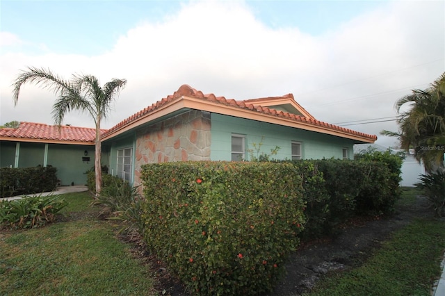 view of property exterior featuring stone siding and a tile roof