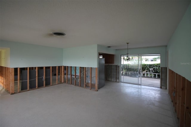 unfurnished room with a chandelier, visible vents, a textured ceiling, and concrete floors