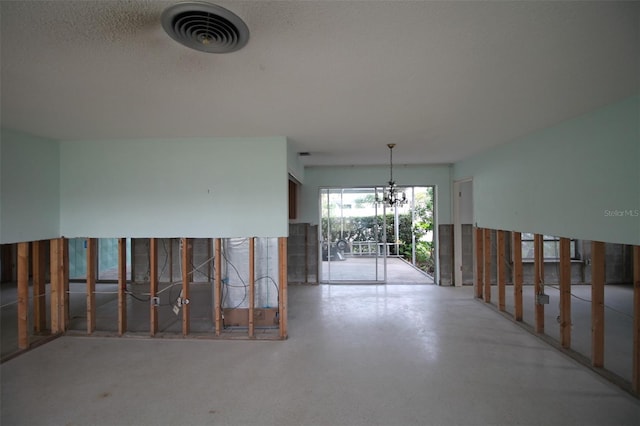 empty room featuring visible vents, a textured ceiling, concrete flooring, and an inviting chandelier