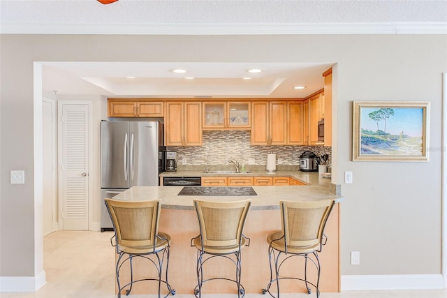 kitchen featuring a sink, a kitchen bar, appliances with stainless steel finishes, and decorative backsplash