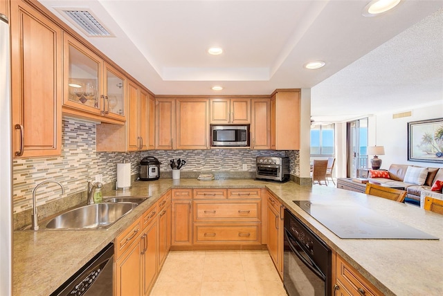 kitchen featuring visible vents, a sink, electric stovetop, stainless steel microwave, and black oven