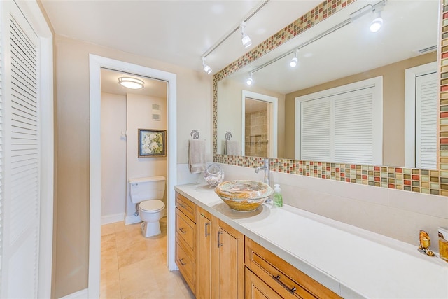 bathroom with a closet, tile patterned floors, toilet, and vanity