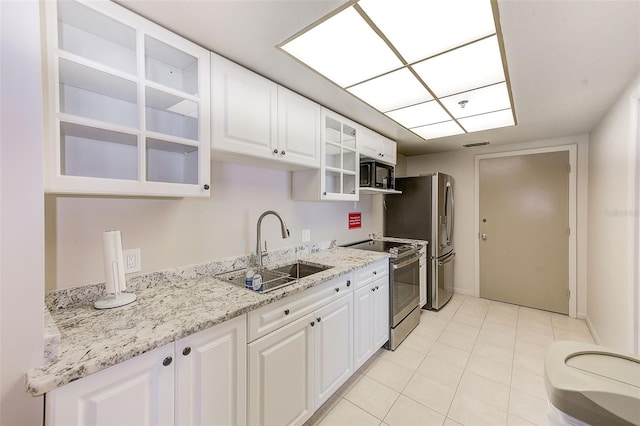 kitchen with visible vents, a sink, stainless steel appliances, white cabinets, and glass insert cabinets