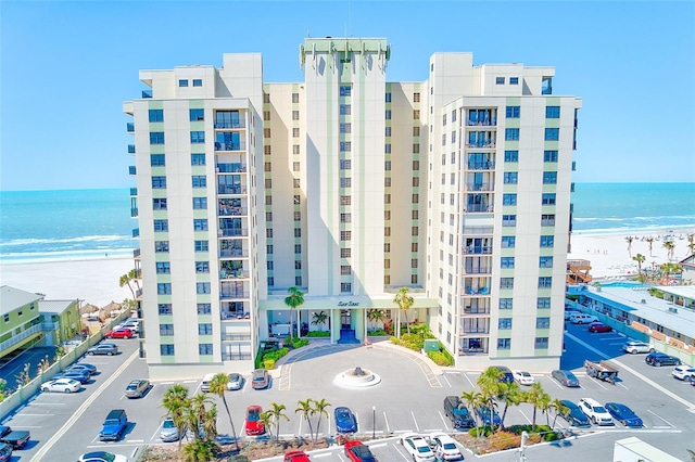 view of property with a beach view, uncovered parking, and a water view