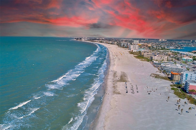 aerial view at dusk featuring a water view, a city view, and a view of the beach